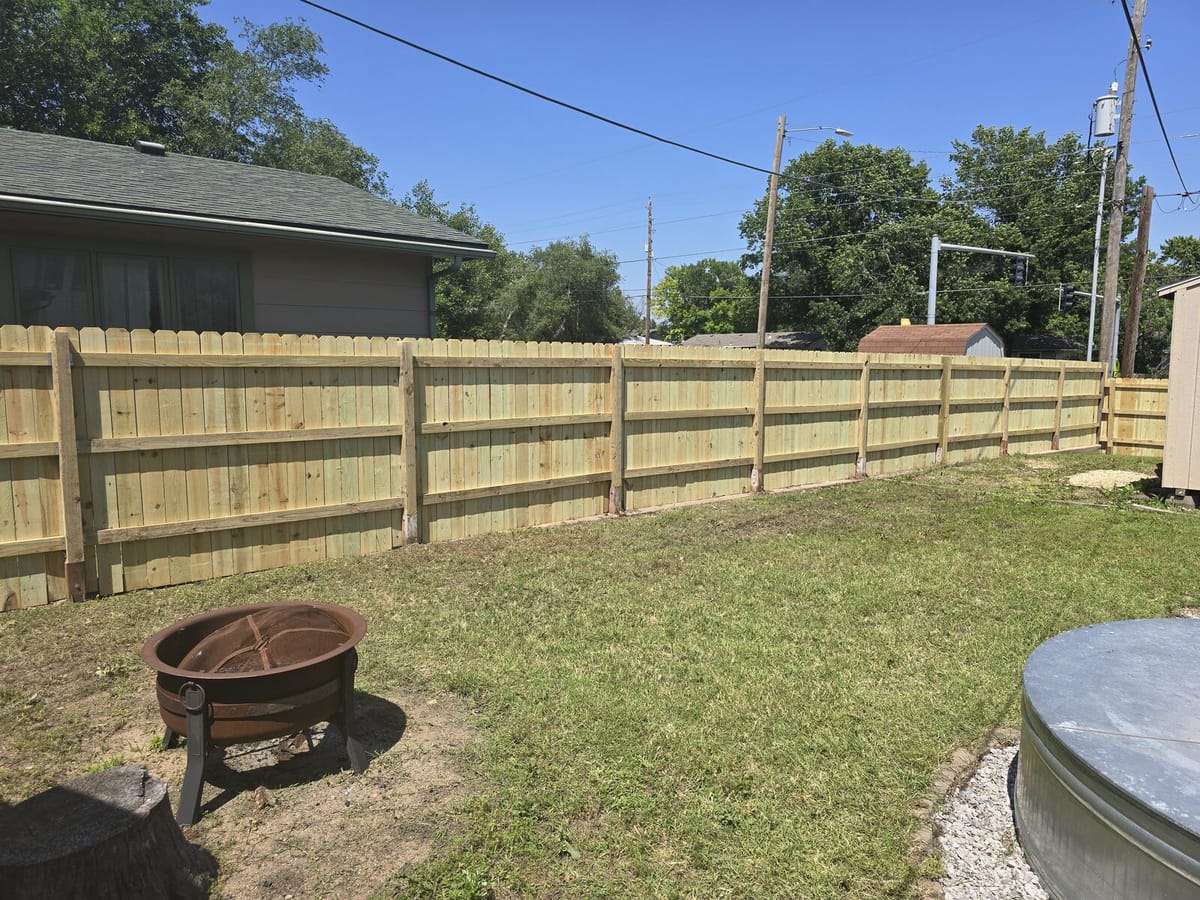 Long cedar privacy fence in an open Wichita yard with a fire pit